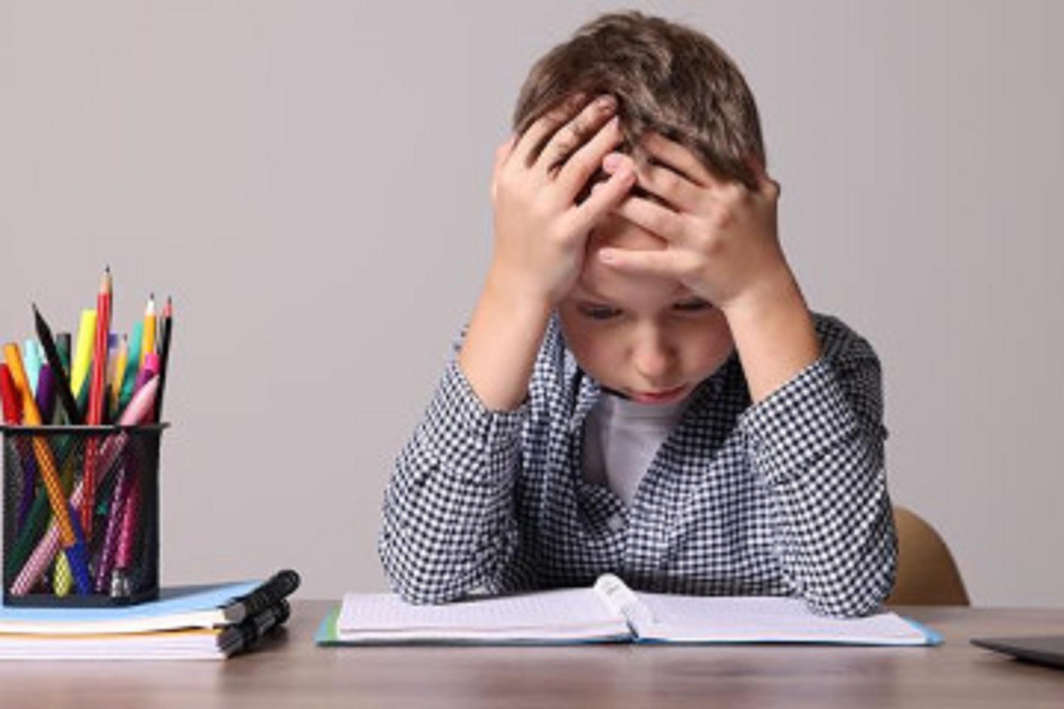 A young boy sitting at a table trying to learn
